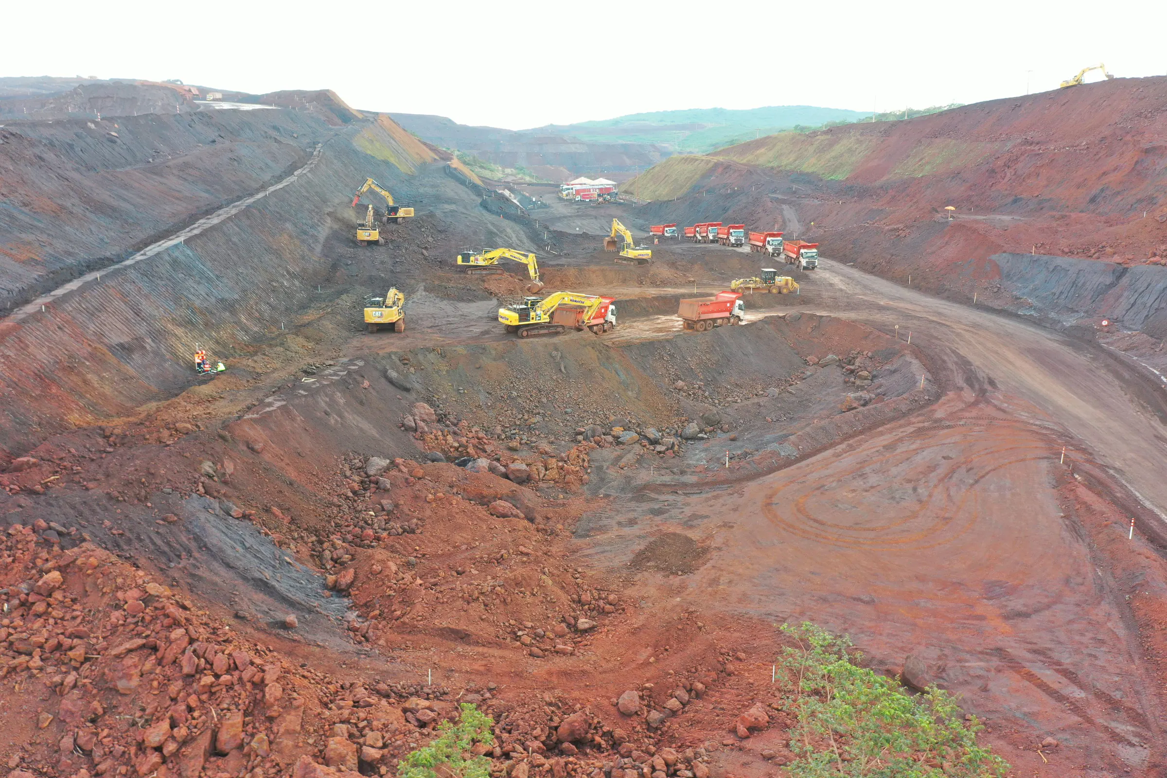 Escavadeiras e caminhões basculantes em bancada de mina a céu aberto