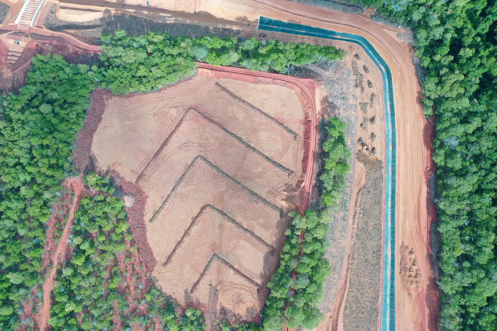Vista aérea de área em recuperação com drenagem em espinha de peixe, ao lado de canal revestido