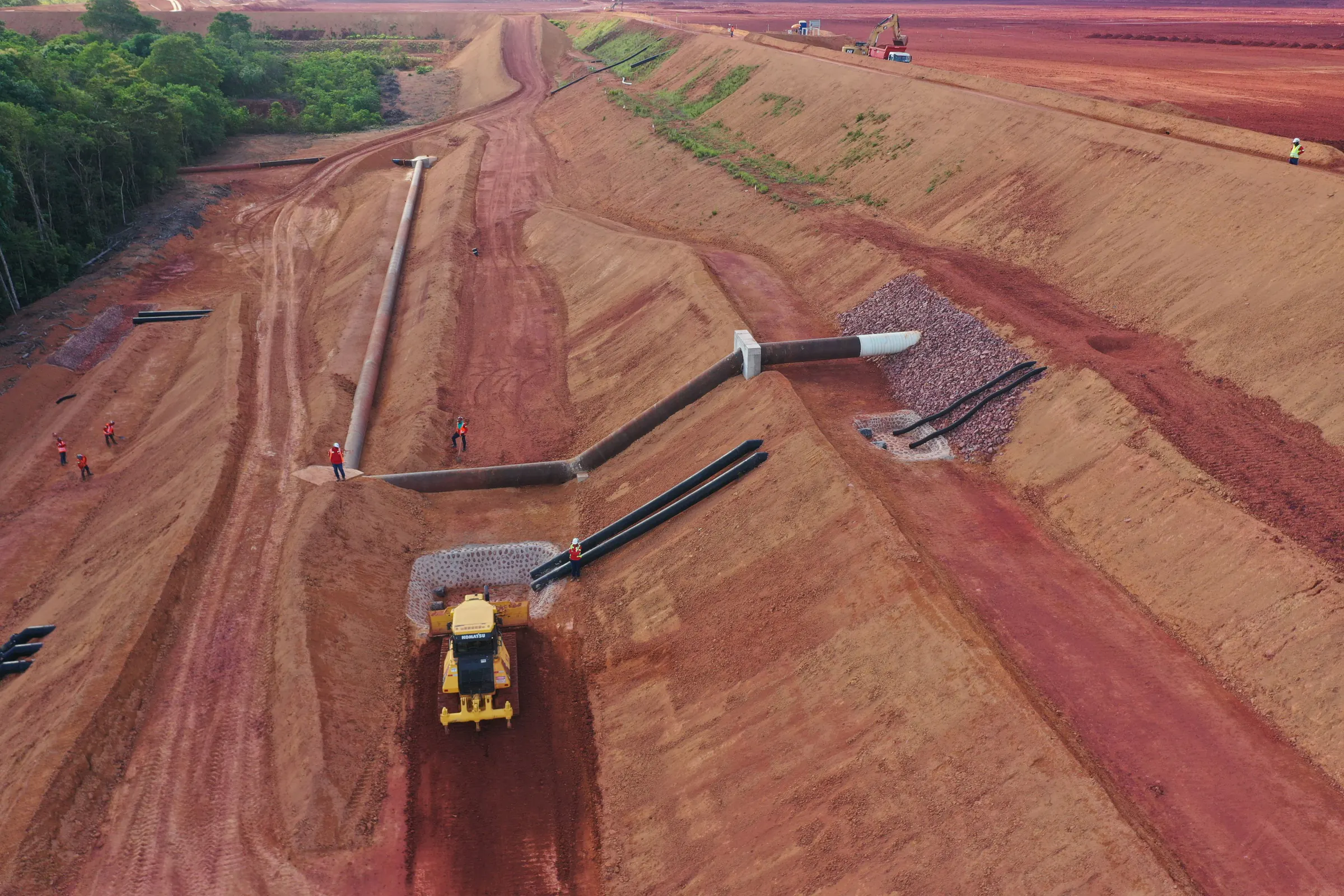 Vista aérea de área de terraplenagem com canais de drenagem revestidos e trator de esteira em operação